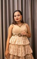 an Asian woman wearing a brown dress while attending a prom night at school photo