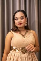 an Asian woman wearing a brown dress while attending a prom night at school photo