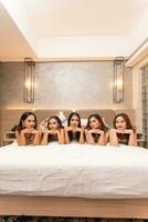 a group of Asian women are lying on white mattresses with their friends in a hotel photo