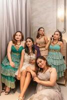 a group of Asian women in luxurious dresses are waiting for dinner in a hotel ballroom photo