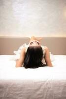 an Asian woman with black hair is sleeping on a white bed in an elegant hotel photo