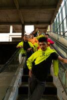 a group of Asian men in lemon green jackets are standing with their friends on the escalator photo