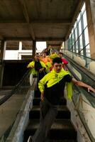 un grupo de asiático hombres en limón verde chaquetas son en pie con su amigos en el escalera mecánica foto