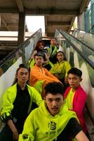 un grupo de asiático hombres son relajante en el escalera con su amigos a un Universidad foto