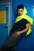 an Asian man posing stylishly while wearing a green hoodie in front of a locker photo