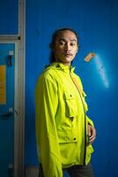 an Asian man in a green jacket is posing in front of a blue door photo