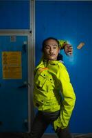 an Asian man in a green jacket is posing in front of a blue door photo