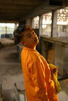 an Asian man standing in front of the window of an abandoned building while wearing a yellow blazer photo