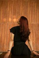 an Asian man with long hair is sitting in front of a brown wooden background photo