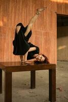 an Asian man is doing a breakdance on a brown table while wearing a black shirt photo