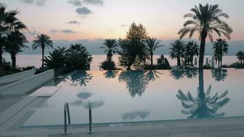 Sunset scene of resort with swimming pool overlooking the sea and palms, Turkey video