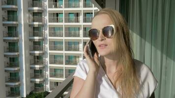alegre mujer teniendo móvil teléfono hablar en el balcón video