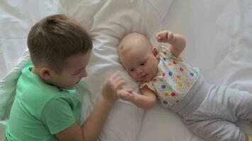 Boy and baby girl siblings on bed at home video