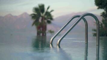 Open pool with shiny railing against palm trees and mountains video