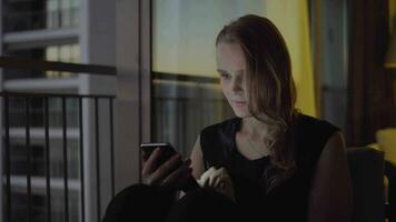 Woman surfing internet on cell being bored at home in the evening video