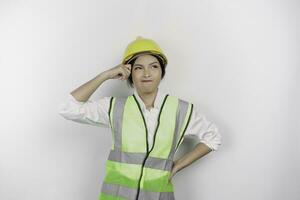 A thoughtful young woman labor worker wearing safety helmet and vest is looking aside to an idea on copy space , isolated by white background. Labor's day concept. photo