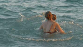 mãe com filho tomando banho dentro ondulado mar video