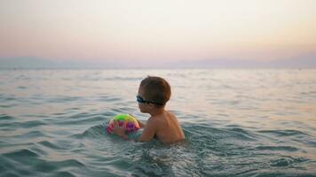 bambino assunzione palla per acqua e poi galleggiante su esso nel il mare video