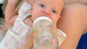 Mother giving baby daughter to drink water from the bottle video