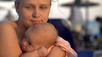 sognante madre con bambino su il spiaggia a tramonto video