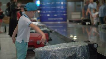 Junge suchen zum seine Koffer auf Gepäck Förderer Gürtel beim das Flughafen video