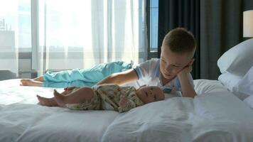 Boy and baby sister on the bed at home video