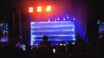 A slow motion of a crowd in front of the bright stage at an open air concert video