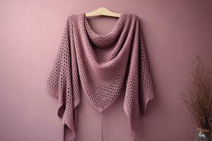 A mauve crocheted shawl, made of a soft, lightweight fabric, draped elegantly over a hanger. Soft fabric texture, neutral background, warmth and coziness concept. AI Generated. photo