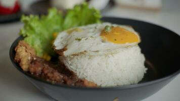 Rice bowl with sunny side up egg, chicken, vegetables and lettuce on white table in restaurant. photo