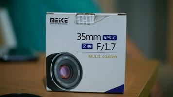 Meike 35mm lens box on wooden table. Third party provider of lenses for digital cameras. photo