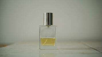 Small transparent perfume bottle filled with yellow liquid on table with minimalist blurry background. photo