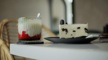 A glass of strawberry drink and chocolate cheesecake on white table in cafe. photo