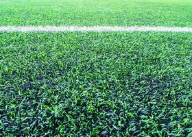 Texture of plastic artificial grass and the rubber pellets on school yard photo