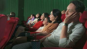 divers mensen zijn aan het kijken saai bioscoop in film theaters. Aziatisch gezinnen, vrienden, en groepen van publiek in stoelen hebben slecht uitdrukkingen samen, binnen- vermaak levensstijl met film shows. video