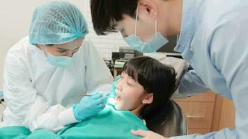 asiático hembra pediátrico dentista cheques y examina muchachas dientes con su padre alentado en dental clínica, bienestar higiene, y profesional ortodoncia cuidado de la salud médico en niños hospital. video