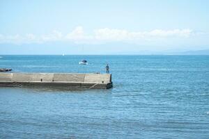 fisherman standing with seaview west coast at Enoshima Iwaya Cave place in the west end of Enoshima Island in Fujisawa, Kanagawa, Japan photo