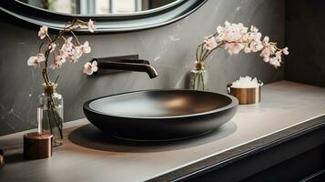 Close up chic bathroom with oval sink, empty countertop, wooden vanity, black framed mirror, flower and grey wall. Generative AI photo