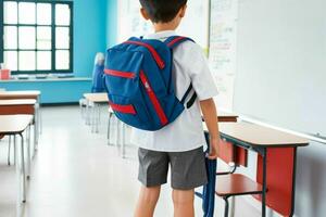Back view of a schoolboy with a backpack standing in the classroom. Pro Photo