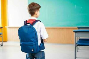 Back view of a schoolboy with a backpack standing in the classroom. Pro Photo