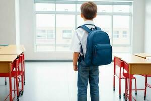 Back view of a schoolboy with a backpack standing in the classroom. Pro Photo