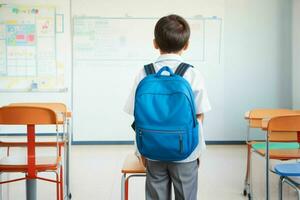 Back view of a schoolboy with a backpack standing in the classroom. Pro Photo