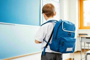 Back view of a schoolboy with a backpack standing in the classroom. Pro Photo