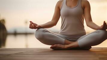 Side view of crop unrecognizable female in sportswear sitting in lotus pose with fingers in mudra while practicing yoga on wooden pier. Generative AI photo