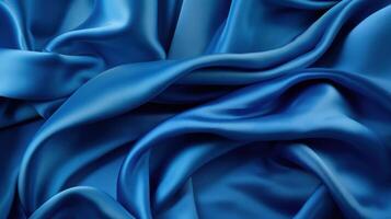 A blue silk cloth is draped over a table with soft light on it, dark blue fabric material background, photo