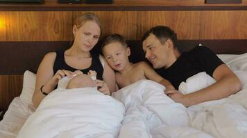 feliz pais com crianças deitado dentro cama juntos video