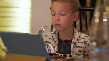 Child having meal and watching touch pad in cafe video