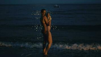 mãe com bebê desfrutando mar brisa às noite video