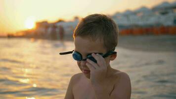 niño en gafas de protección es yendo a bañarse a puesta de sol video