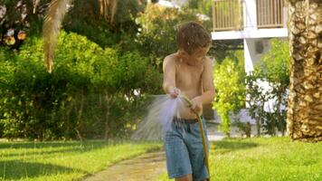 Boy watering the lawn and getting wet video