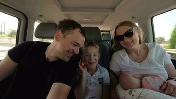 Happy parents with elder son and baby daughter having car journey video